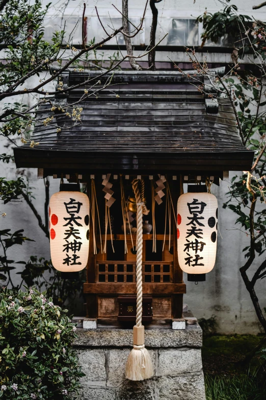 a couple of lanterns hanging from the side of a building, inspired by Kanō Shōsenin, trending on unsplash, an altar of a temple, wooden house, portrait photo, hyperdetailed