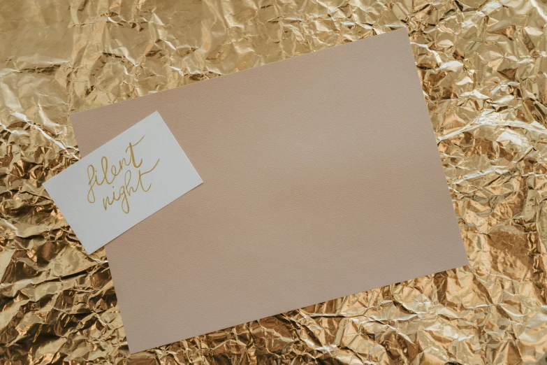 a note sitting on top of a piece of foil, pexels contest winner, beige color scheme, night!, background image, on high-quality paper