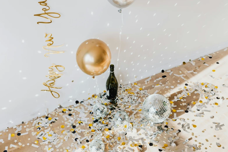 a champagne bottle sitting on top of a table covered in confetti, by Julia Pishtar, baloons, silver and gold, detailed product image, winter vibes