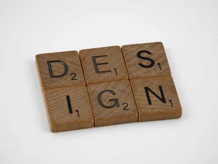 a wooden block with the word design written on it, a digital rendering, unsplash, grid arrangement, idealised, military design, set against a white background