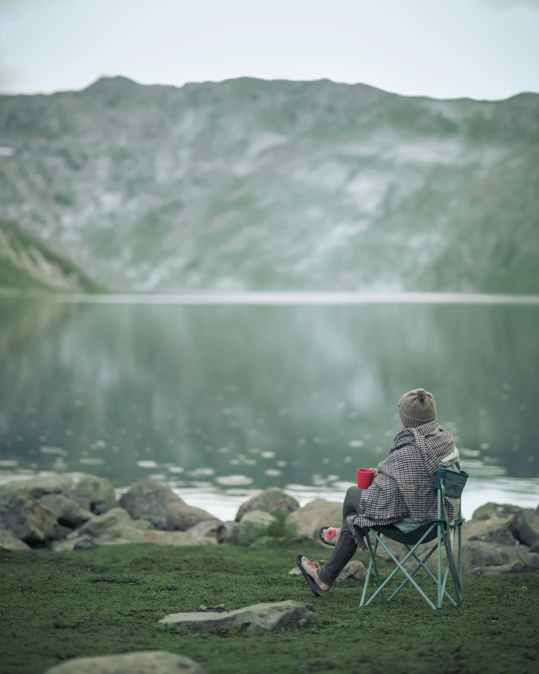 a person sitting in a chair next to a body of water, pexels contest winner, camping, grey, green water, cinematic