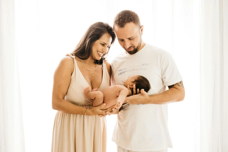 a man standing next to a woman holding a baby, pexels, avatar image, brunette, brazilian, holding intimately