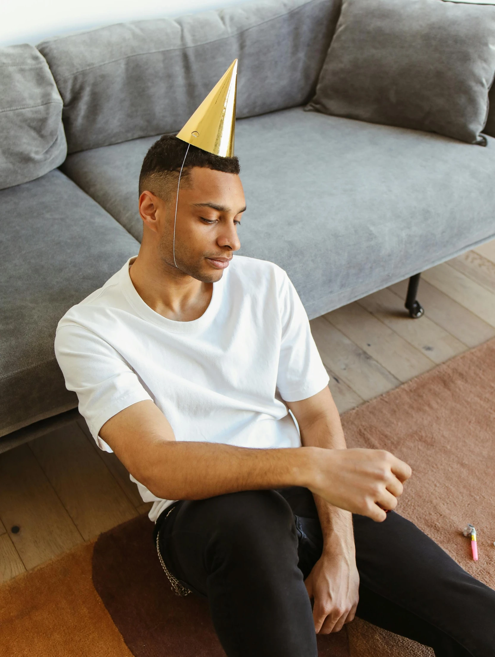 a man sitting on the floor wearing a party hat, a colorized photo, trending on unsplash, happening, lean man with light tan skin, gold shirt, thumbnail, happy birthday