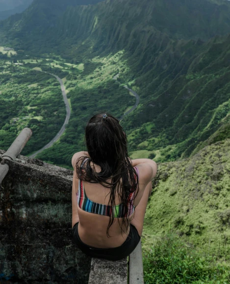 a woman sitting on a ledge overlooking a valley, by Hannah Tompkins, pexels contest winner, hawaii, halter top, low quality photo, multiple stories