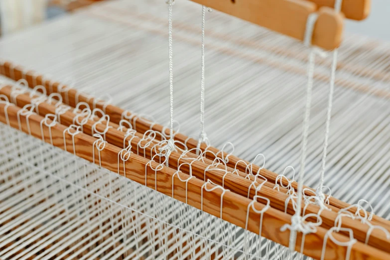 a close up of a weaving loom on a loom, by Carey Morris, trending on pexels, arts and crafts movement, silver，ivory, large chain, a wooden, white