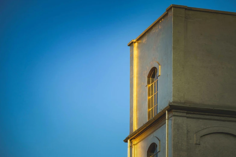 a clock that is on the side of a building, an album cover, inspired by William Nicholson, unsplash contest winner, minimalism, bathed in golden light, lookout tower, blue, ignant