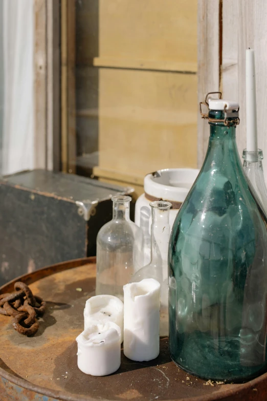 a green glass bottle sitting on top of a wooden barrel, a still life, unsplash, old furnitures, blue, milk, museum photograph