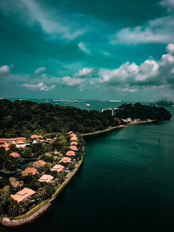 a large body of water next to a lush green hillside, a tilt shift photo, pexels contest winner, happening, singapore ( 2 0 1 8 ), waterfront houses, islands!!!!!, drone footage