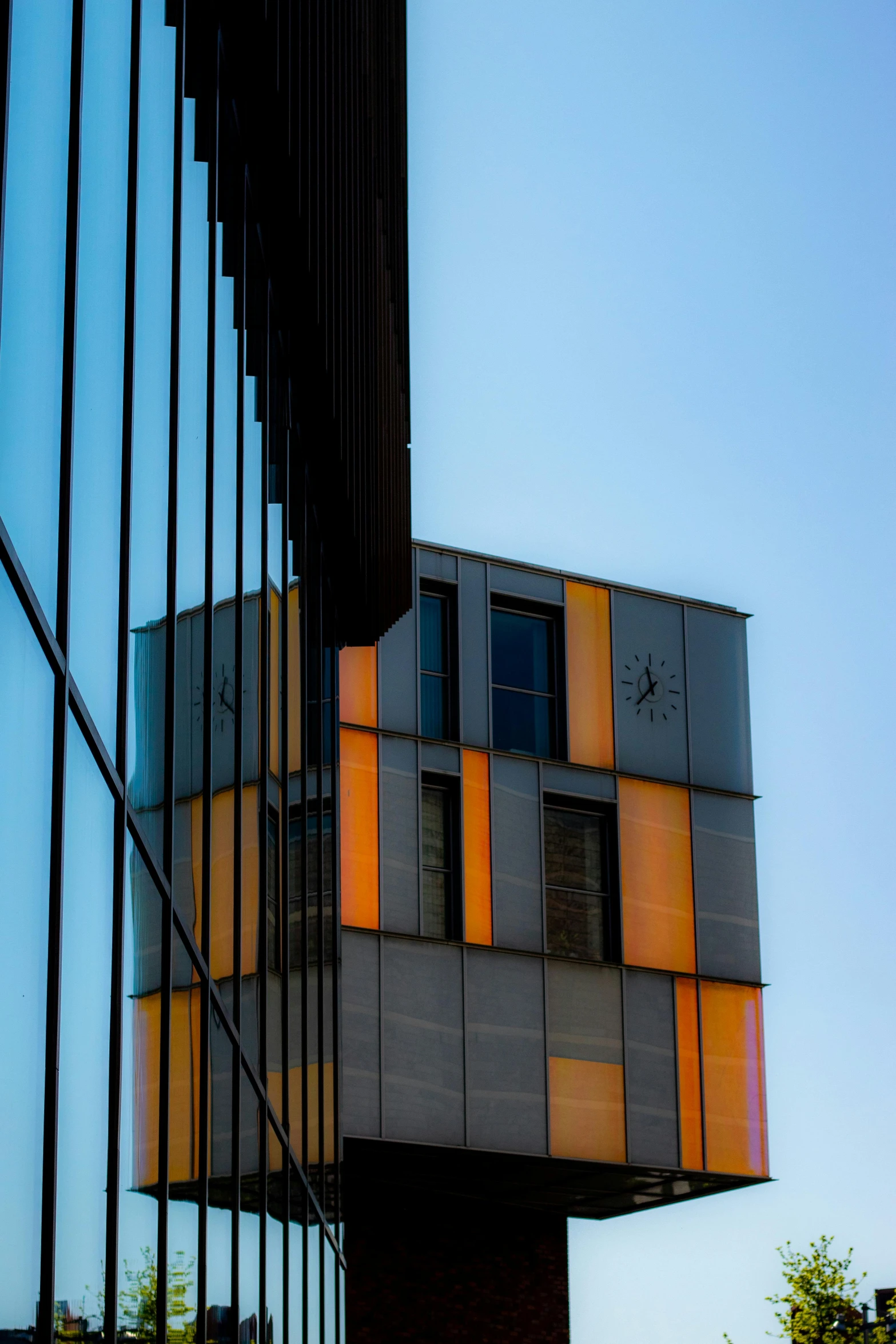 a building is reflected in the windows of another building, by Doug Ohlson, unsplash, modernism, gray and orange colours, evening light, utrecht, morphosis