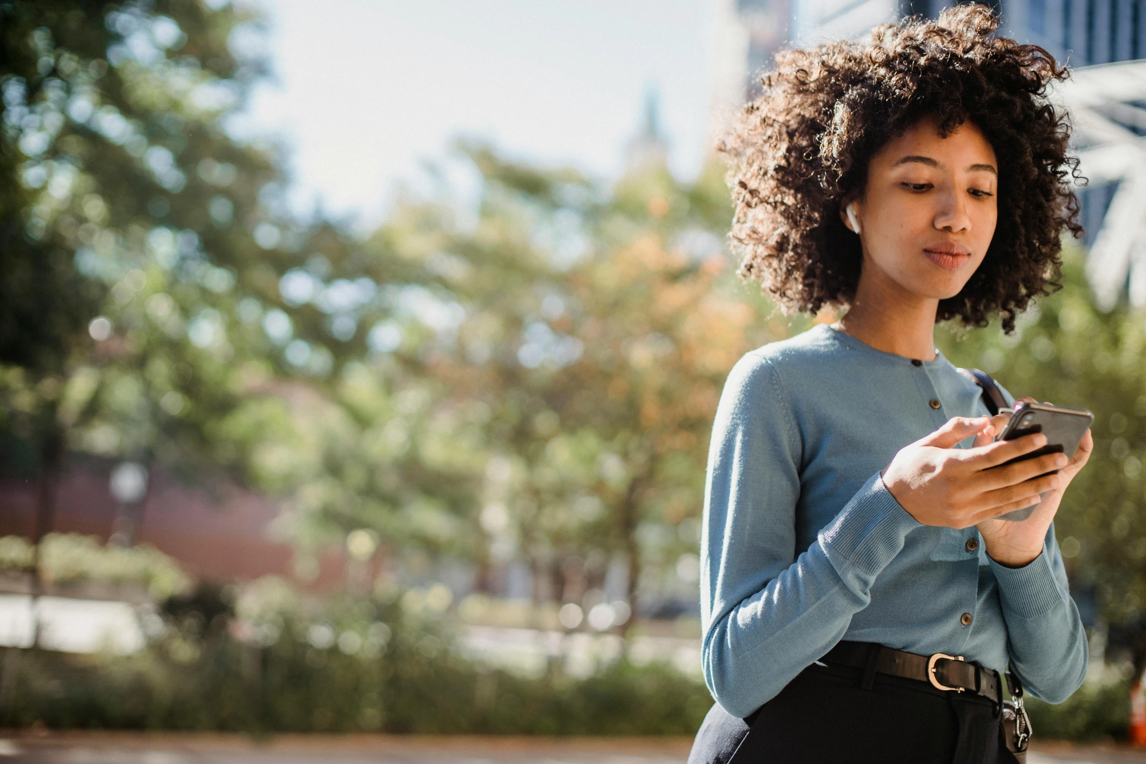 a woman is looking at her cell phone, trending on pexels, with afro, walking to the right, programming, schools