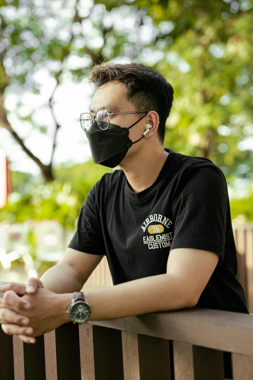 a man sitting on a bench wearing a face mask, wearing a black shirt, south east asian with round face, premium quality, wear ray - ban glass