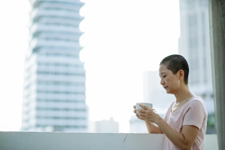 a woman standing on a balcony holding a cup of coffee, inspired by Cui Bai, pexels contest winner, 4 5 yo, ethnicity : japanese, profile image, thinning hair