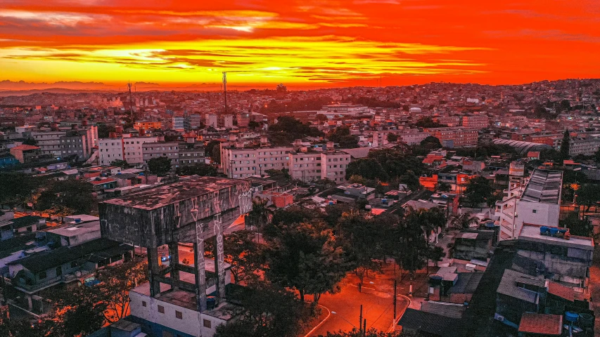 an aerial view of a city at sunset, a photo, by Luis Miranda, red sun over paradise, cuban setting, blood red colored sky, city on the background