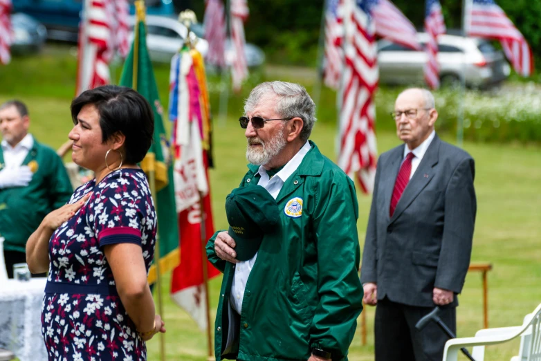 a man in a green jacket standing next to a woman, by Gene Davis, unsplash, american flags, ceremony, avatar image, marine