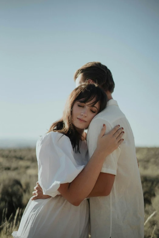 a couple hugging each other in a field, unsplash, romanticism, in a desert, overlooking, soft shade, say