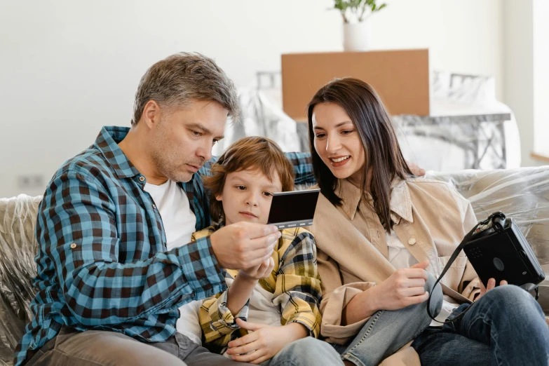 a couple of people that are sitting on a couch, he is holding a smartphone, husband wife and son, everything fits on the screen, uploaded