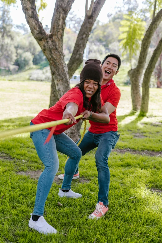 two people playing tug rope in a park, happening, holding a spear, red shirt brown pants, bay area, avatar image