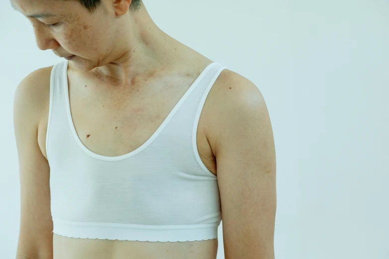 a close up of a person wearing a white shirt, inspired by Ren Hang, unsplash, shin hanga, detailed sports bra, recovering from pain, very thin, thin young male