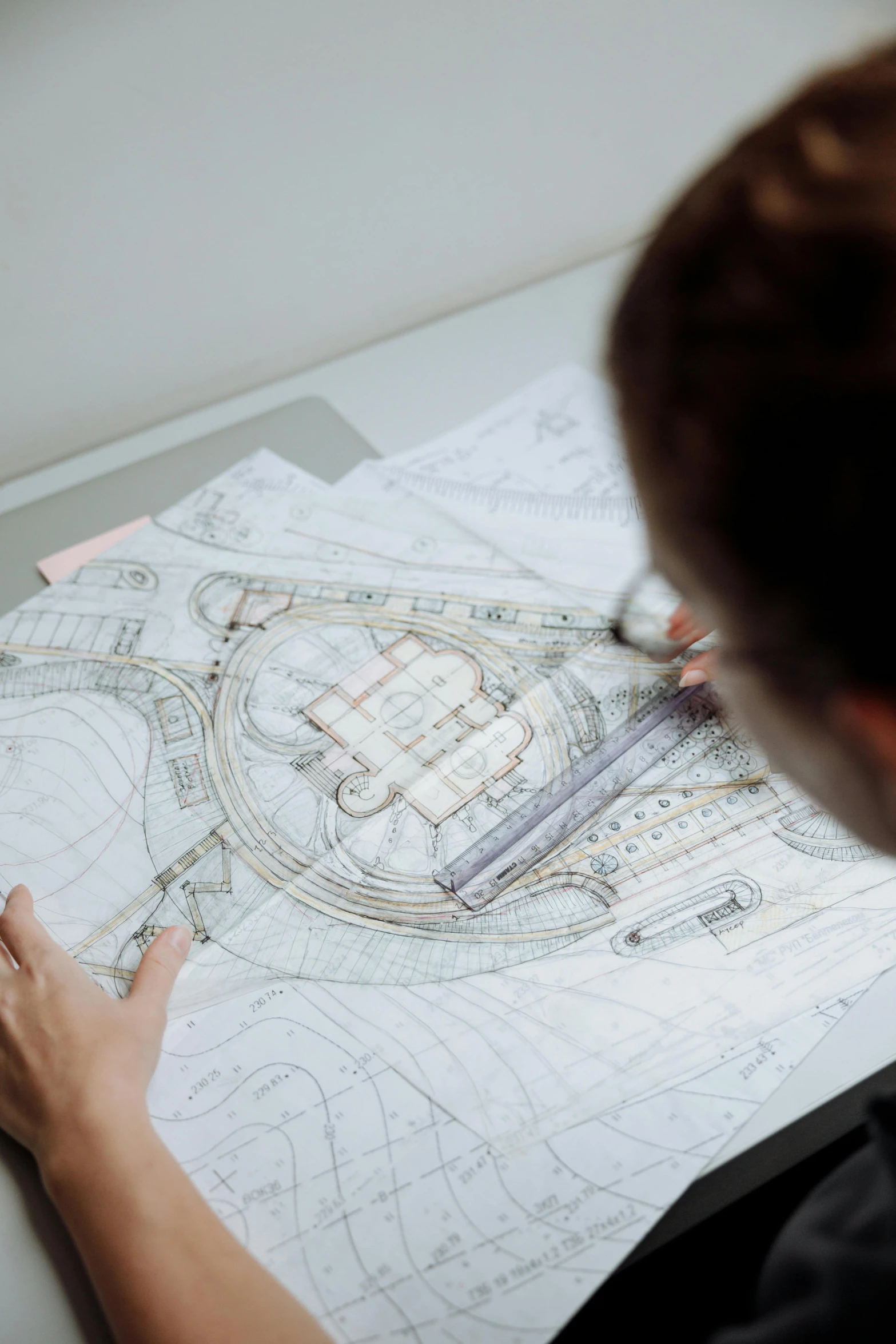 a woman is looking at a drawing on a table, a detailed drawing, foster and partners, zoomed in, promo image, cartographic