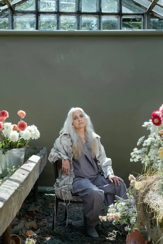 a woman sitting in a chair in a greenhouse, an album cover, unsplash, renaissance, long silver hair with a flower, laura letinsky and steve mccurry, older woman, 15081959 21121991 01012000 4k