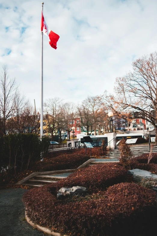 a flag on a pole in front of a building, an album cover, inspired by Edward Willis Redfield, trending on unsplash, vancouver school, park landscape, hong soonsang, panoramic shot, hell gate