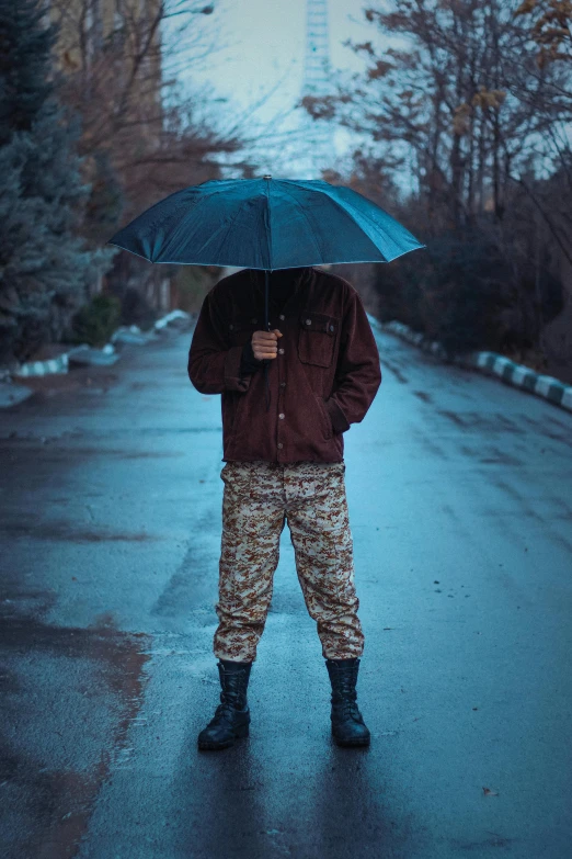 a man standing in the middle of a road holding an umbrella, military pants, instagram picture, scumbled, non-binary