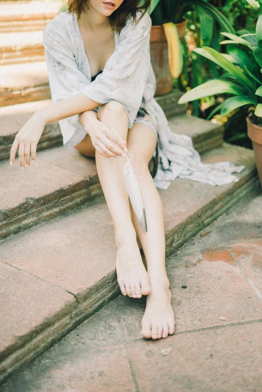 a woman sitting on the steps of a house, unsplash, renaissance, bare foot, wearing silver silk robe, thigh gap, swollen veins