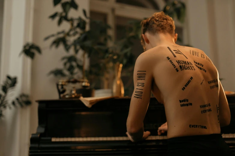 a man with tattoos on his back sitting at a piano, pexels contest winner, queer woman, a labeled, human structure, upper body image