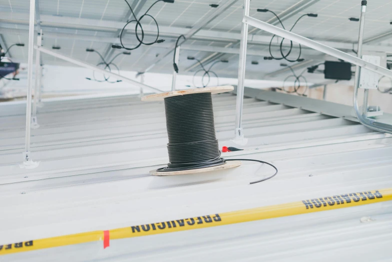 a spool of thread sitting on top of a conveyor belt, rooftop solar panels, dark cables hanging from ceiling, farming, promo image