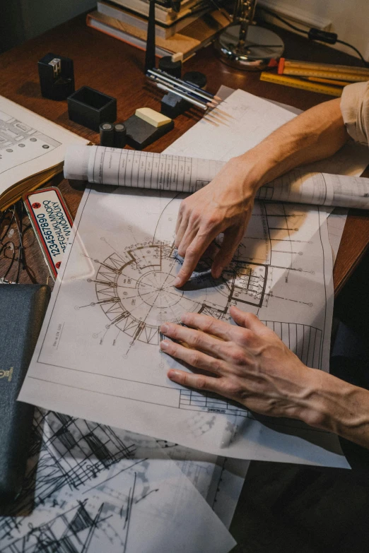 a man sitting at a table working on a blueprint, a detailed drawing, pexels contest winner, circular shape, collectors, manly design, rectangle