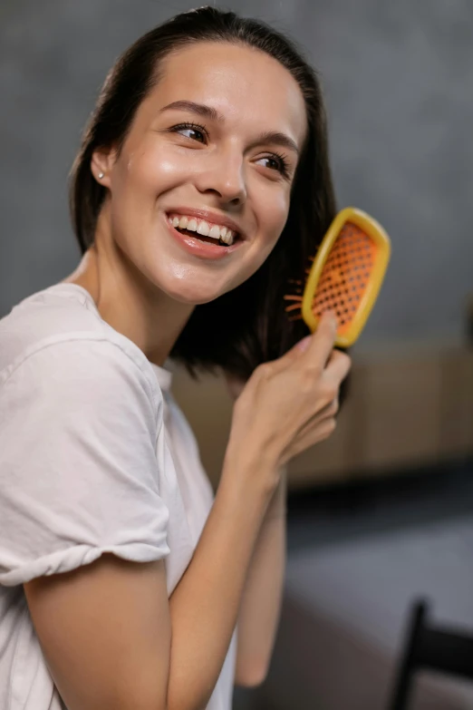 a woman smiles as she brushes her hair, pexels contest winner, gel spiked hair, rectangle, detailed product image, yellow