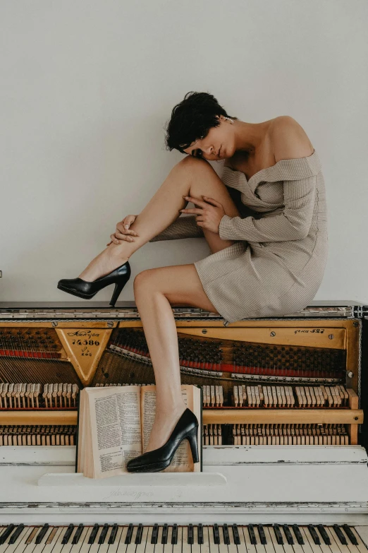 a woman sitting on top of a piano, stilettos, curated collection, non binary model, 2019 trending photo