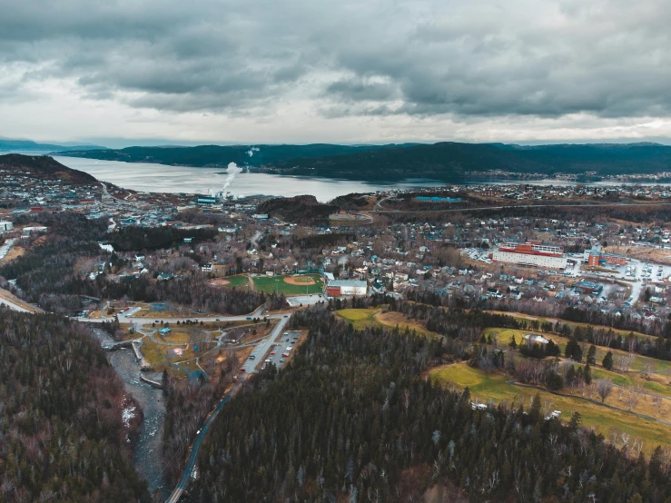 an aerial view of a town with mountains in the background, by Jesper Knudsen, pexels contest winner, happening, quebec, gloomy skies, ultrawide angle cinematic view, high quality product image”