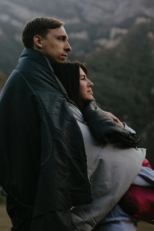 a man and a woman standing next to each other, pexels contest winner, wearing jacket, overlooking, cuddling, high detaild