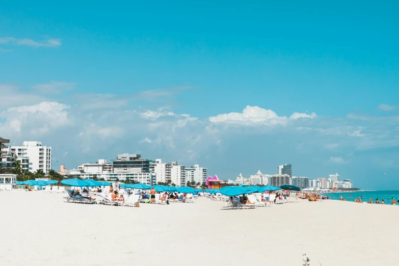 a beach filled with lots of people and umbrellas, by Carey Morris, pexels contest winner, miami vice, sunny day with clear sky, oscar niemeyer, skyline