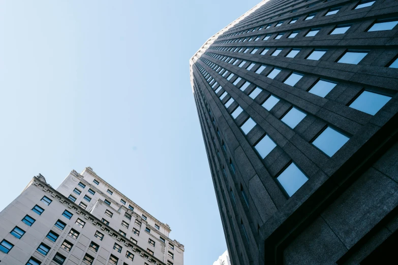 a couple of tall buildings next to each other, by Adam Rex, unsplash contest winner, clear blue skies, tall obsidian architecture, 2 0 0 0's photo, low angle view