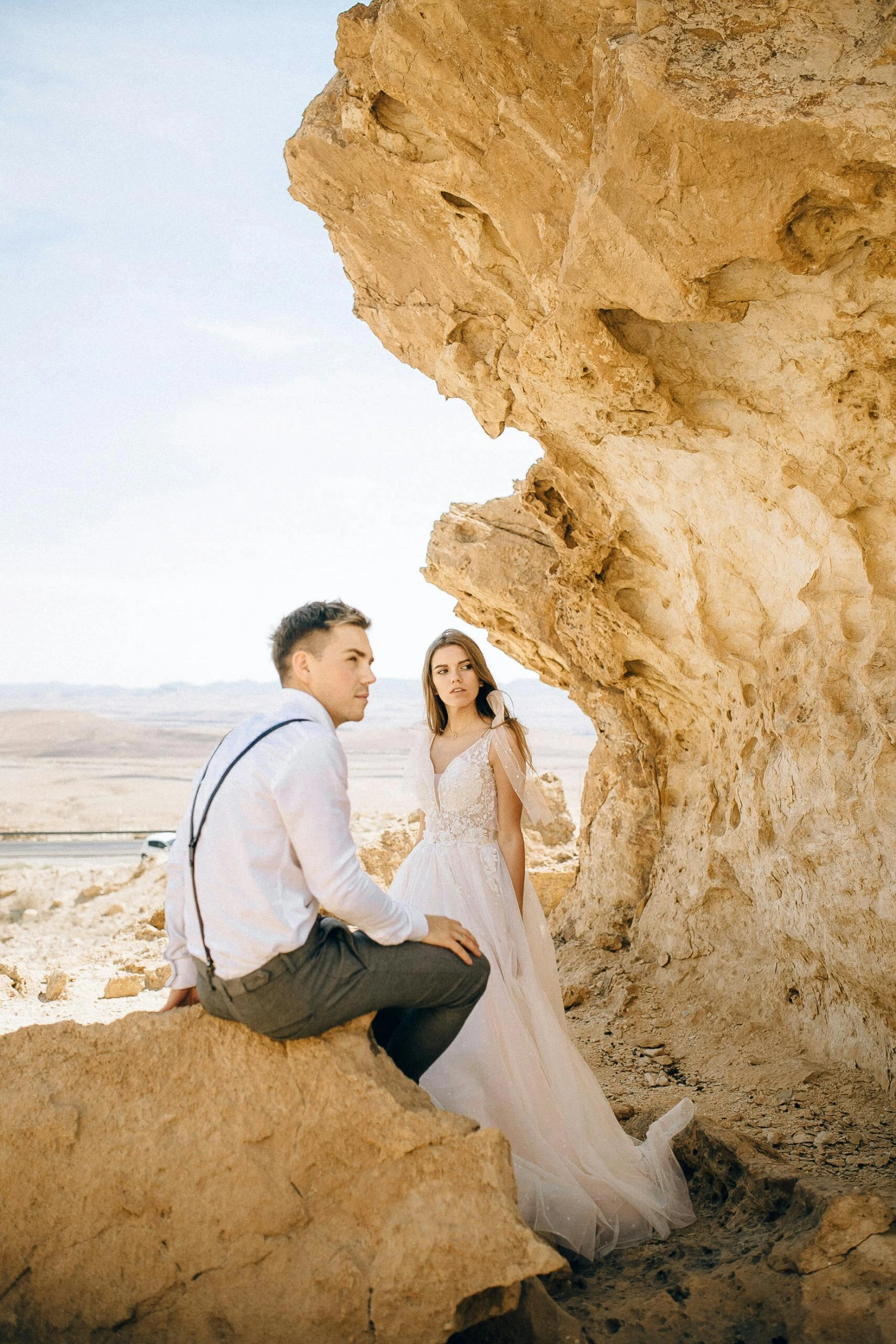 a man and a woman sitting on a rock, a picture, by Saul Yaffie, pexels contest winner, romanticism, desert robe, israel, bride and groom, slide show