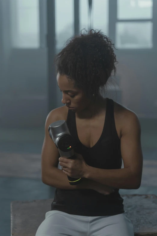 a woman sitting on a bench holding a hair dryer, in a gym, pitch black skin, wētā fx, holding a torch