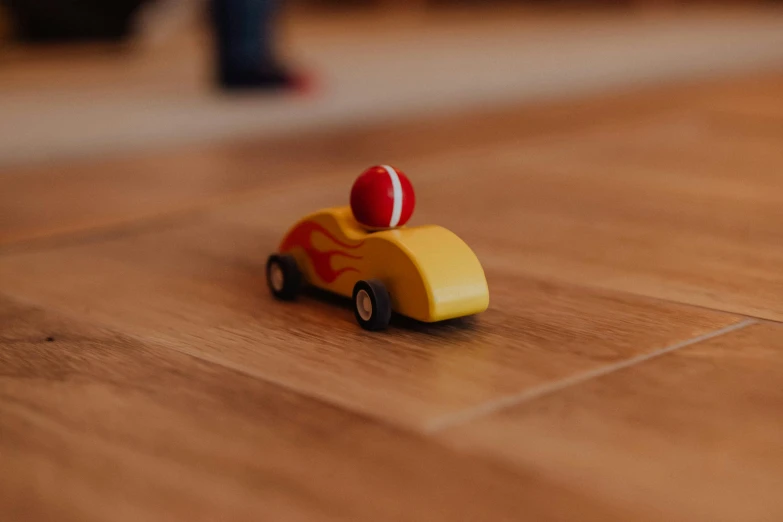 a toy car sitting on top of a wooden floor, pexels contest winner, fireball, activity play centre, tiny feet, wood effect