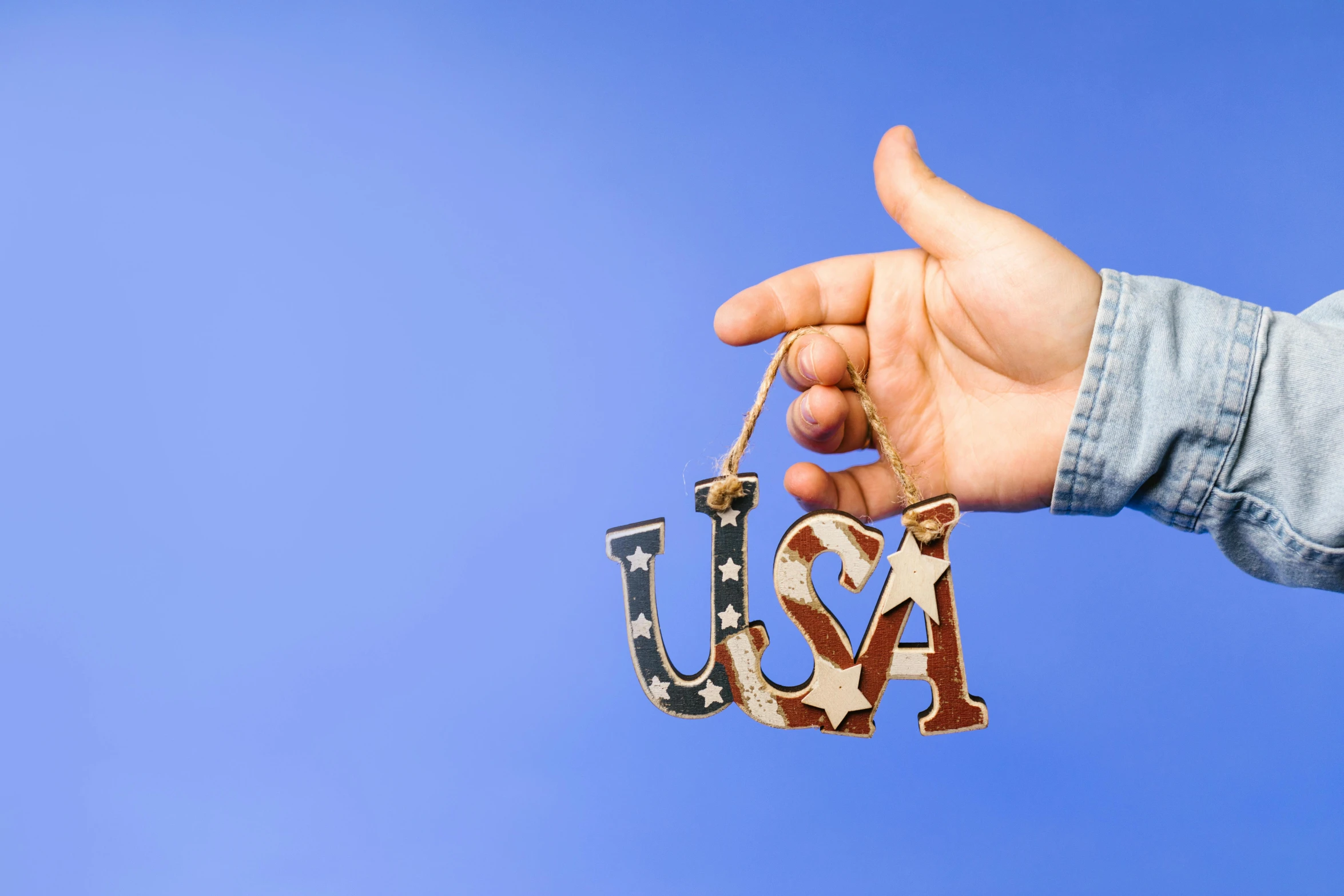 a person holding an ornament with the word usa on it, an album cover, trending on unsplash, folk art, background image, uk, independence, laser cut