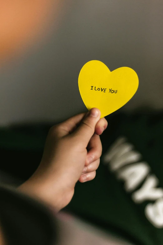 a person holding a yellow heart with i love you written on it, by Julia Pishtar, pexels, diecut, 👅 👅