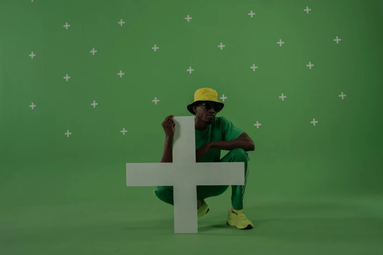 a man sitting on top of a white cross, an album cover, trending on pexels, wearing green clothing, ( ( dark skin ) ), acids, character with a hat