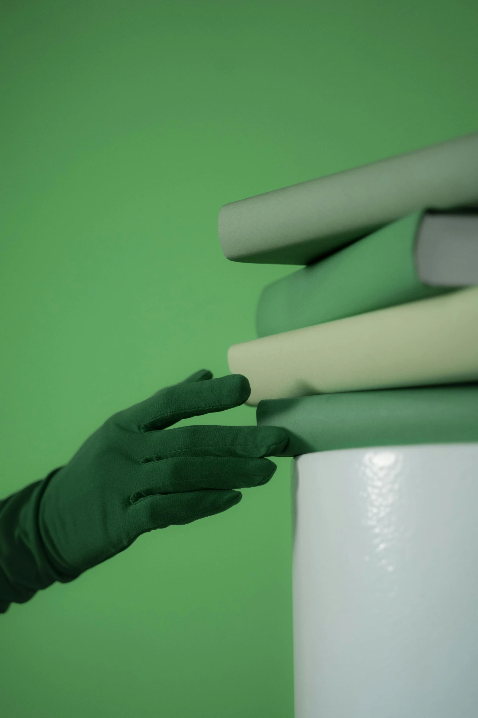 a person in green gloves holding a stack of books, inspired by Robert Mapplethorpe, unsplash, conceptual art, plaster, tubes, solid colors, photographed for reuters