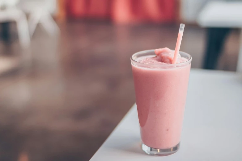 a pink smoothie sitting on top of a table, by Tom Bonson, unsplash, multiple stories, milkshake, background image