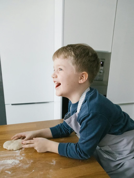 a little boy that is sitting on a table, on kitchen table, dough sculpture, making the best smug smile, taken in 2 0 2 0