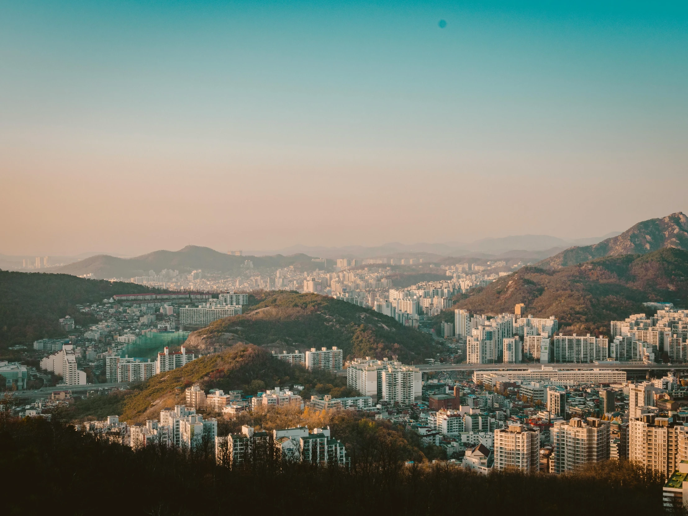 a view of a city from the top of a hill, by Jang Seung-eop, pexels contest winner, hills in the background, warm light, rectangle, instagram post