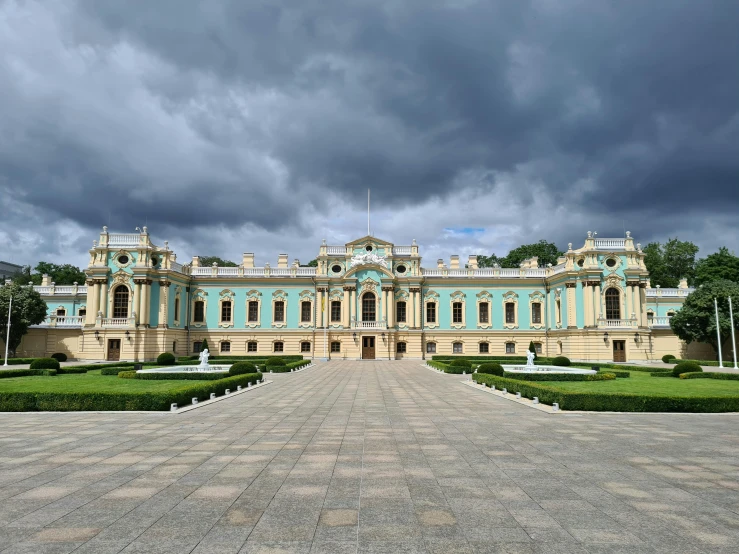 a large building sitting on top of a lush green field, pexels contest winner, neoclassicism, with ominous storm clouds, stanisław, square, rococo color scheme