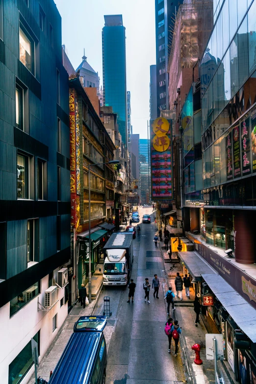 a city street filled with lots of tall buildings, by Patrick Ching, pexels contest winner, art nouveau, wet market street, late afternoon, high angle shot, alley