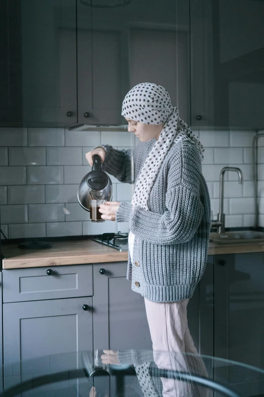 a woman standing in a kitchen preparing food, a colorized photo, pexels contest winner, hurufiyya, wearing a sweater, kettle, gif, arab