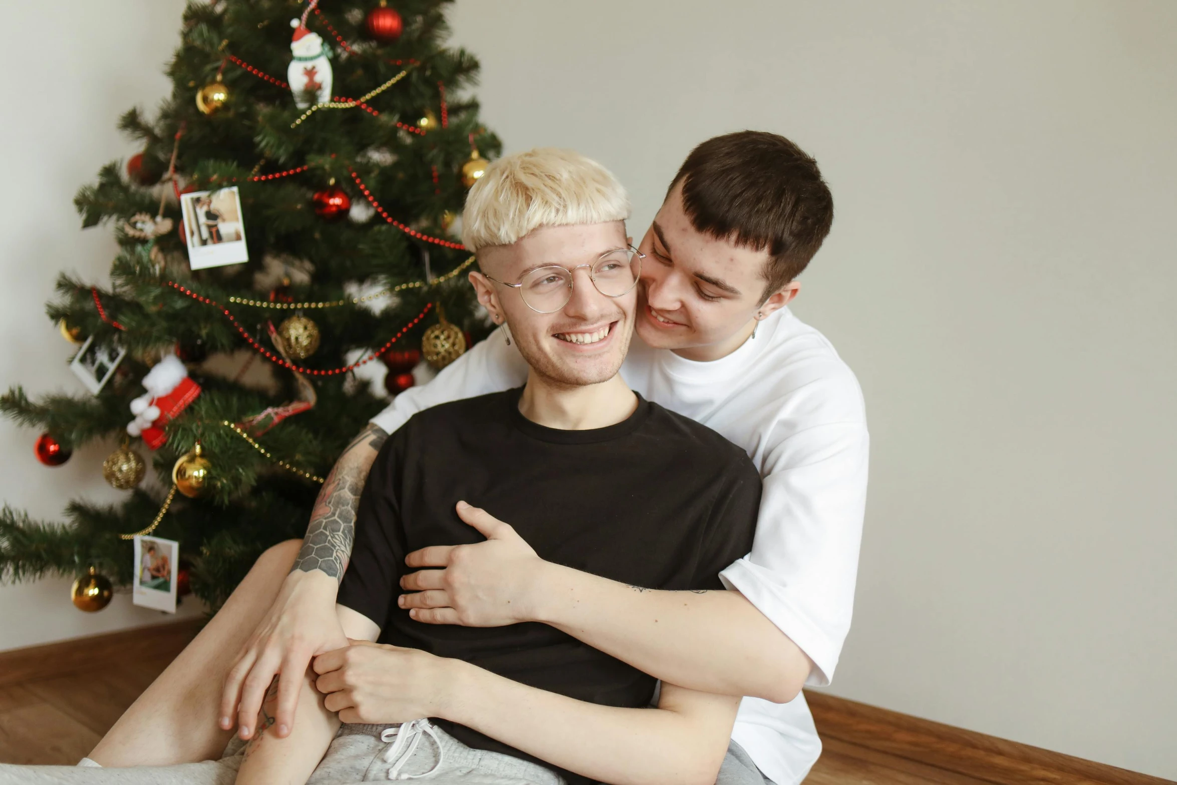 two men sitting next to each other in front of a christmas tree, a photo, pexels, lesbian embrace, albino hair, two buddies sitting in a room, daniil kudriavtsev